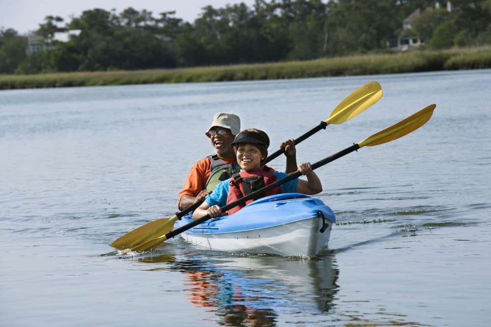 African,American,Middle-aged,Couple,Smiling,And,Paddling,Kayak.